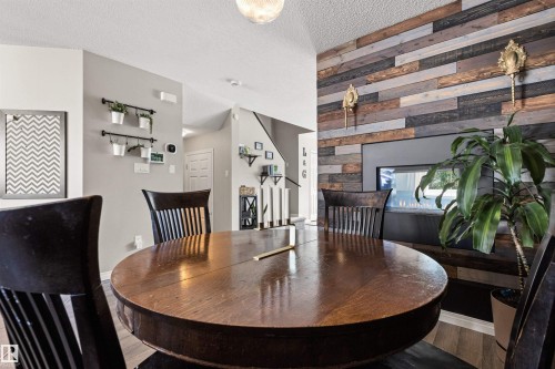 Accent wall featuring horizontal wood planks, built-in linear fireplace, wood-finish flooring, and vaulted ceiling - 4306 Prowse Link Link Sw, Edmonton, AB 