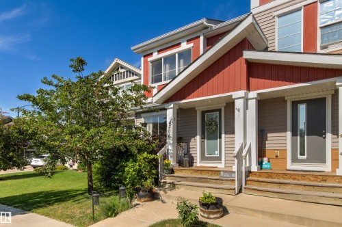 Townhome exterior featuring red and beige siding, white trim, and a gabled roofline - 4306 Prowse Link Link Sw, Edmonton, AB 