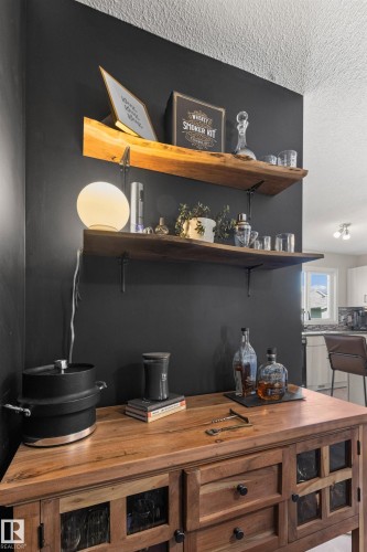 Solid wood-finish cabinetry with glass-front doors, open shelving with wood-finish tops, and a dark accent wall - 4306 Prowse Link Link Sw, Edmonton, AB 