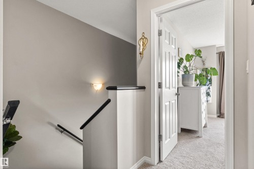 Interior wall sconce lighting, white paneled door, and neutral-toned carpeting - 4306 Prowse Link Link Sw, Edmonton, AB 