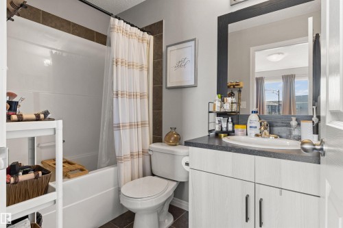 Bathroom featuring a white bathtub, toilet, and vanity with a dark countertop and white cabinetry - 4306 Prowse Link Link Sw, Edmonton, AB 