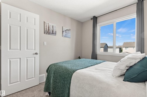 White paneled door, light gray wall paint, large window with white frame, dark gray curtains, and neutral carpet flooring - 4306 Prowse Link Link Sw, Edmonton, AB 