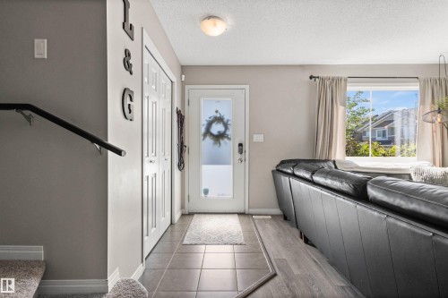 Entryway featuring tile flooring, a frosted glass door, and adjacent wood-finish flooring - 4306 Prowse Link Link Sw, Edmonton, AB 