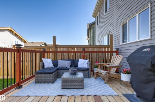 Expansive wood-finish deck with a privacy fence, dark gray siding, and multiple windows - 4306 Prowse Link Link Sw, Edmonton, AB 