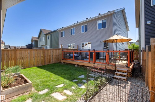 Wood privacy fencing, a wood deck with black metal railings, a manicured lawn, stone stepping pads, and a raised planter box - 4306 Prowse Link Link Sw, Edmonton, AB 