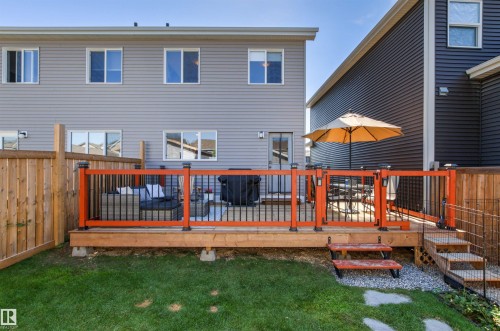 Expansive wooden deck featuring black railings with orange accents and integrated lighting - 4306 Prowse Link Link Sw, Edmonton, AB 