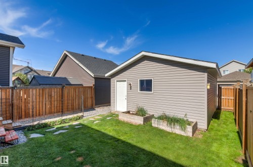 Expansive green lawn, detached outbuilding with siding exterior, privacy fencing, stone walkway, and raised garden beds - 4306 Prowse Link Link Sw, Edmonton, AB 