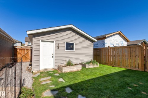 Grassed yard with a detached shed featuring horizontal siding and a white door - 4306 Prowse Link Link Sw, Edmonton, AB 