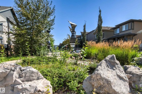 Landscaped communal area featuring decorative rocks, varied plantings, and a modern sculpture - 4306 Prowse Link Link Sw, Edmonton, AB 