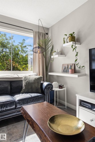 Bright living area with a large window, crown molding, a modern pendant light, and floating wall shelves - 4306 Prowse Link Link Sw, Edmonton, AB 