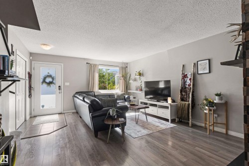 Wood-finish flooring, white trim, recessed lighting fixture, solid core entry door, and a multi-pane window - 4306 Prowse Link Link Sw, Edmonton, AB 