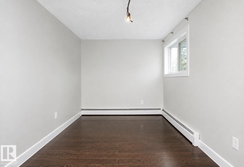 Wood-finish flooring, light gray walls, white trim, track lighting, and a single window - #203 2624 Mill Woods Rd E Nw, Edmonton, AB 