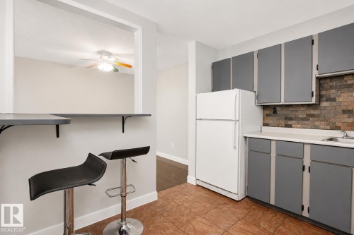 Kitchen featuring grey cabinetry, light countertop, and a tiled backsplash - #203 2624 Mill Woods Rd E Nw, Edmonton, AB 