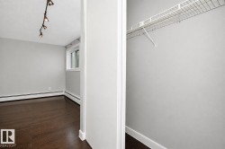 Wood-finish flooring, track lighting, and a window with white trim, complemented by a closet featuring wire shelving - 