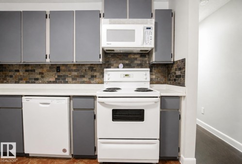 White appliances, subway tile backsplash, white countertops, gray cabinetry, and wood-finish flooring - #203 2624 Mill Woods Rd E Nw, Edmonton, AB 