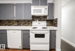 White appliances, subway tile backsplash, white countertops, gray cabinetry, and wood-finish flooring - 