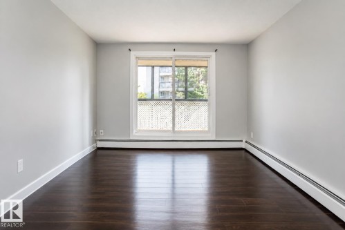 Wood-finish flooring, light gray wall paint, and a sliding glass door with a white frame - #203 2624 Mill Woods Rd E Nw, Edmonton, AB 