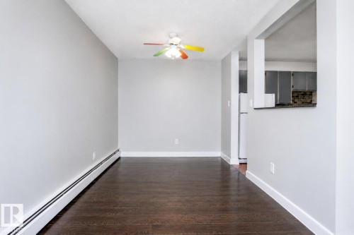 Wood-finish flooring, light gray wall tones, ceiling fan with integrated lighting, white trim, and a pass-through opening to the kitchen - #203 2624 Mill Woods Rd E Nw, Edmonton, AB 