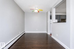 Wood-finish flooring, light gray wall tones, ceiling fan with integrated lighting, white trim, and a pass-through opening to the kitchen - 