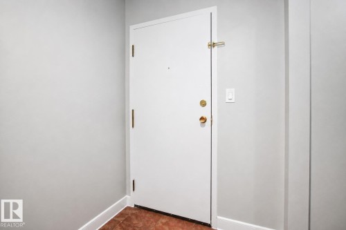 White entry door with brass hardware and tile flooring - #203 2624 Mill Woods Rd E Nw, Edmonton, AB 