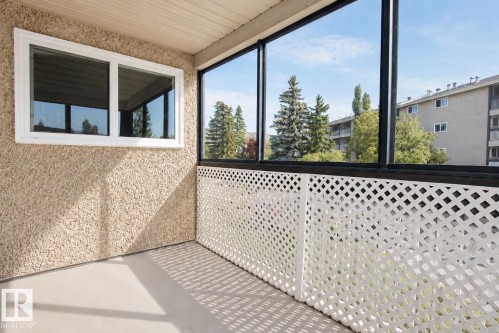 Enclosed balcony featuring a white lattice railing and expansive window - #203 2624 Mill Woods Rd E Nw, Edmonton, AB 