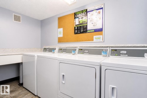 Community laundry facility featuring multiple commercial-grade washers and dryers, a built-in counter space, sink, and light-toned walls - #203 2624 Mill Woods Rd E Nw, Edmonton, AB 