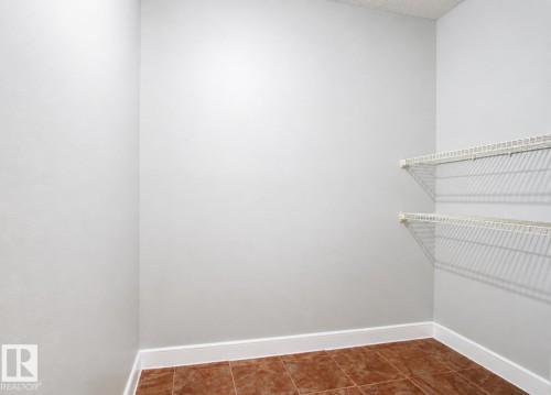 Tile flooring with white baseboards, and two levels of wire shelving - #203 2624 Mill Woods Rd E Nw, Edmonton, AB 