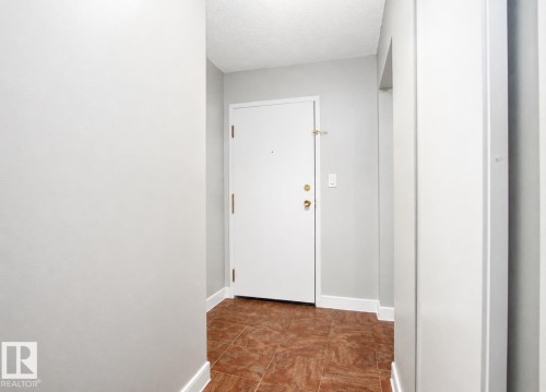 Entryway featuring a white door with brass hardware, light gray walls, and tile flooring - #203 2624 Mill Woods Rd E Nw, Edmonton, AB 