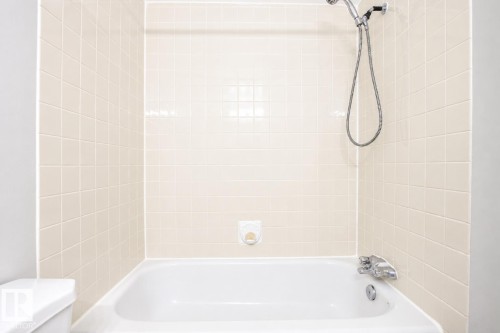 Bathtub with tile surround, showerhead, and chrome fixtures - #203 2624 Mill Woods Rd E Nw, Edmonton, AB 
