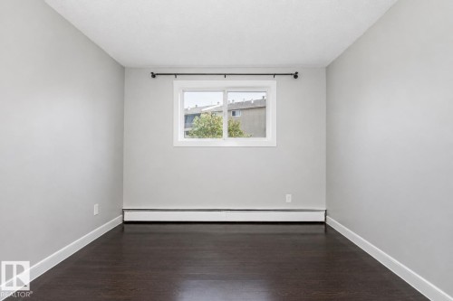 Dark wood-finish flooring with white trim, light gray walls, and a white-framed window - #203 2624 Mill Woods Rd E Nw, Edmonton, AB 