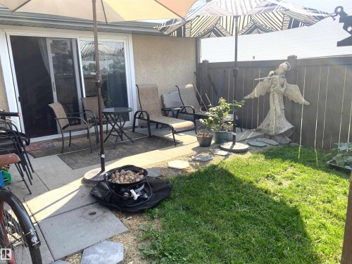 Paved patio area, sliding glass door, privacy fencing, and a grass section - #D1 1 Garden Grove Nw, Edmonton, AB 