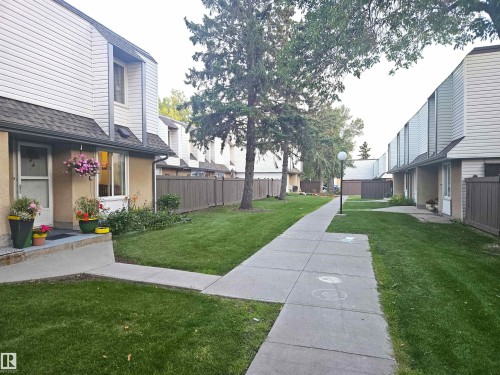 Two-story townhome featuring a neutral-toned exterior, white siding, and a dark shingled roof - #D1 1 Garden Grove Nw, Edmonton, AB 