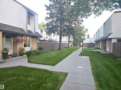Two-story townhome featuring a neutral-toned exterior, white siding, and a dark shingled roof - 