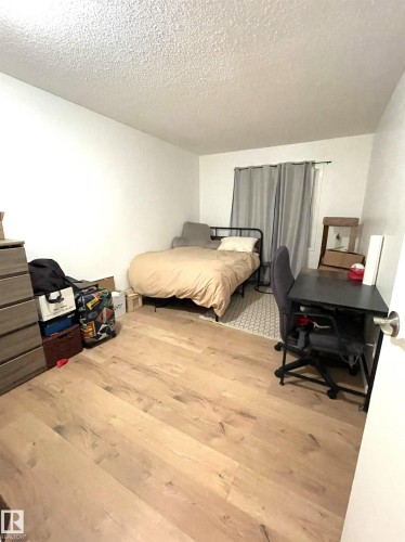 Wood-finish flooring throughout the room, bright white walls, and a window with neutral drapery - #D1 1 Garden Grove Nw, Edmonton, AB 
