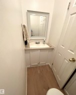 Powder room featuring a framed mirror, a vanity with a drop-in sink, white cabinetry, and wood-finish flooring - 
