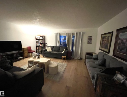 Light wood-finish flooring throughout, white walls, and a recessed window with neutral drapes - #D1 1 Garden Grove Nw, Edmonton, AB 