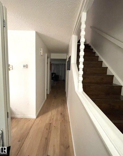 Hardwood-finish flooring, white painted walls, wood staircase with white balusters, and a textured ceiling - #D1 1 Garden Grove Nw, Edmonton, AB 