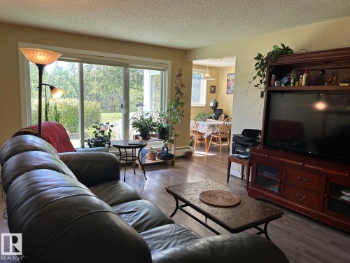 Wood-finish flooring throughout, sliding glass door leading to an outdoor space, and built-in media console - #112 4404 122 St Nw, Edmonton, AB 