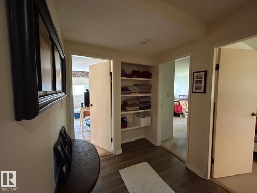 Wood-finish flooring throughout, complemented by a built-in shelving unit - #112 4404 122 St Nw, Edmonton, AB 