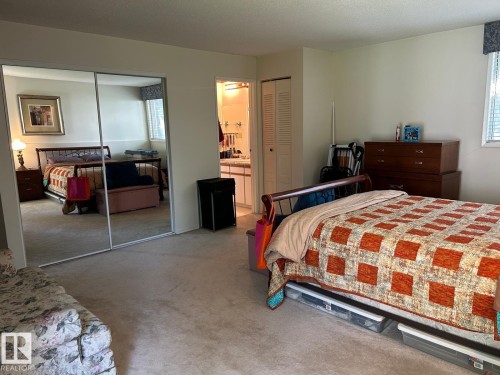 Mirrored closet doors, carpet flooring, and a bathroom entry with a vanity - #112 4404 122 St Nw, Edmonton, AB 