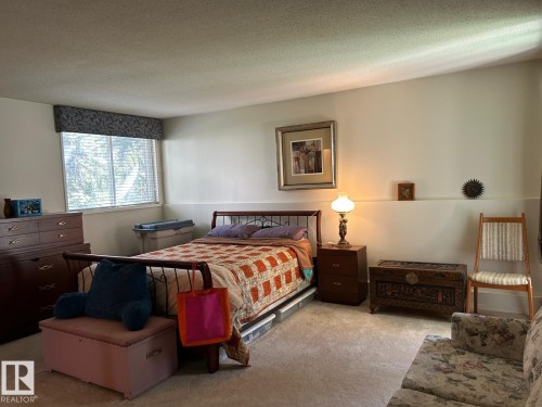 Carpeted room featuring a window with blinds, a built-in wall shelf, and light-toned walls - #112 4404 122 St Nw, Edmonton, AB 