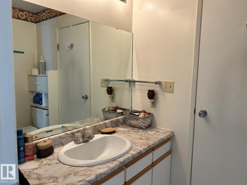 Vanity with an integrated sink, laminate countertop, and wood-trim cabinetry - #112 4404 122 St Nw, Edmonton, AB 