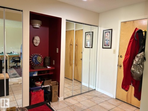 Tile flooring, mirrored closet doors, built-in shelving, and light wood-finish interior doors - #112 4404 122 St Nw, Edmonton, AB 