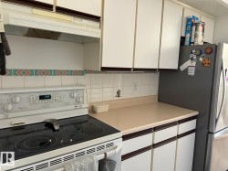 White cabinetry with wood-finish trim, ceramic tile backsplash, smooth-top electric range, and laminate countertops - 