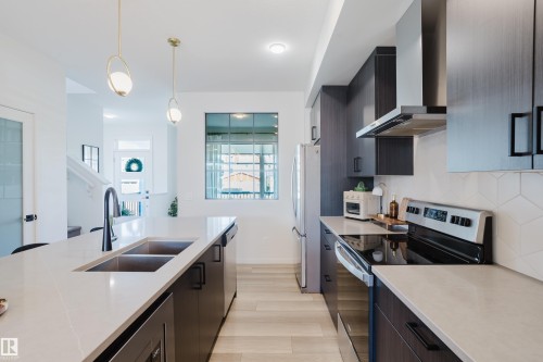 Modern kitchen featuring dark wood-finish cabinetry, stainless steel appliances, and light countertops - 7017 52 Avenue, Beaumont, AB 