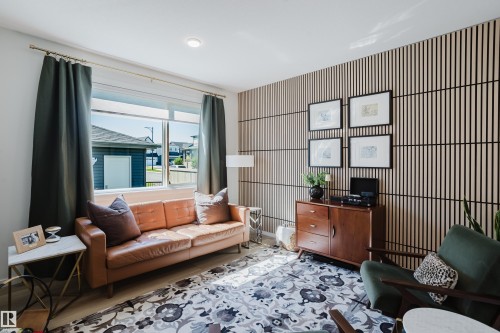 Recessed ceiling lighting, large window with ample natural light, decorative wall paneling, and wood-finish flooring - 7017 52 Avenue, Beaumont, AB 
