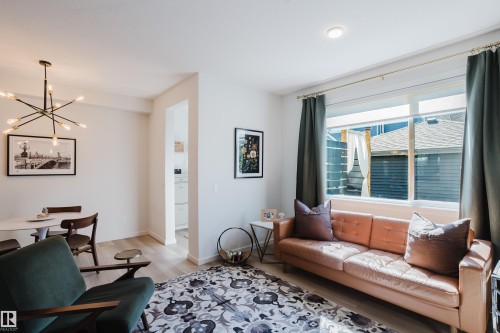 Open-concept living space featuring wood-finish flooring, recessed lighting, a multi-pane window, and a modern sputnik chandelier - 7017 52 Avenue, Beaumont, AB 