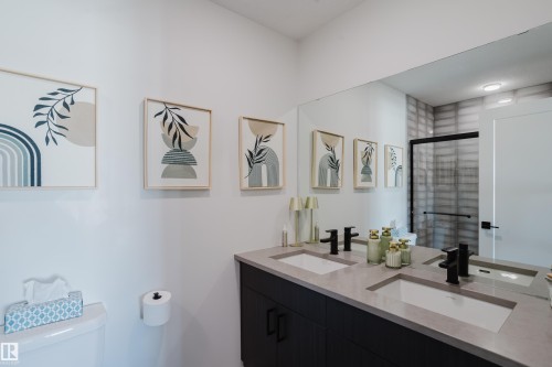 Dual vanity with integrated sinks, stone-finish countertop, and matte black fixtures - 7017 52 Avenue, Beaumont, AB 