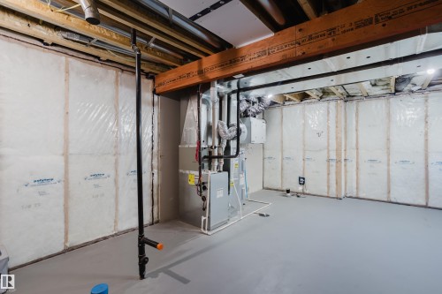 Unfinished basement with exposed ceiling joists, insulation, and concrete flooring - 7017 52 Avenue, Beaumont, AB 