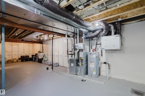 Unfinished basement with exposed ceiling joists, insulated exterior walls, painted concrete flooring, and visible HVAC ductwork - 7017 52 Avenue, Beaumont, AB 